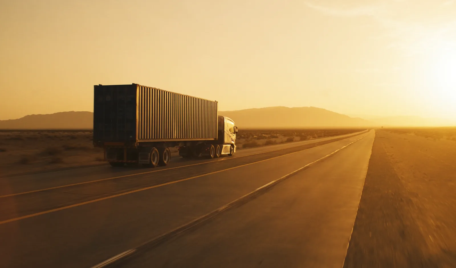 Container truck on an open highway at golden hour, the road stretching toward the horizon
