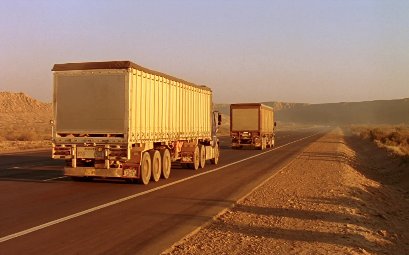 Curtain-side trailers on a desert highway at late afternoon