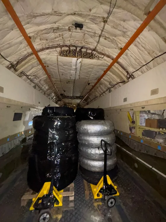 Pallet trucks moving wrapped cargo into position inside the aircraft hold