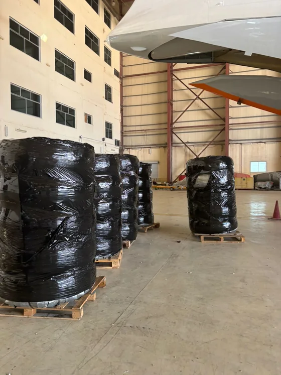 Wrapped cargo on wooden pallets staged beside the aircraft before loading