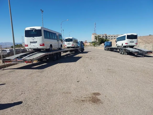 Three new buses secured on flatbed trailers ready for delivery
